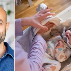 Man ler mot kameran medan en bebis sveps in i en filt. Kanske förbereds för ett barntvål test.