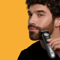 Man trimmar polisonger med en trimmer.