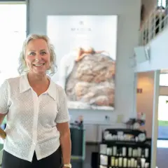 En kvinna ler vid en trappa. Bakom henne syns en stor bild med texten "MARIA ÅKERBERG".