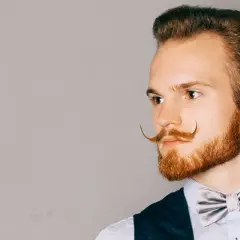 Man med imponerande mustasch stilar, en elegant fluga och en snygg frisyr.