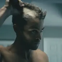 Man raka huvudet i spegeln, med en intensiv blick.