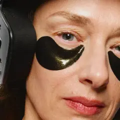 Närbild på en kvinna med mogen hud, bärandes svarta ögonlappar och hörlurar.