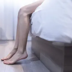 En person sitter på sängkanten, benen dinglar. Kanske en huskur mot restless legs kan ge ro.