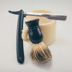 Rakborste, mugg och rakkniv redo för att slipa rakblad för en perfekt rakning.