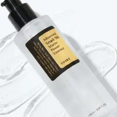 En flaska med COSRX Advanced Snail 96 Mucin Power Essence, en populär produkt inom snigelslem hudvård, omgiven av dess klara, geléaktiga konsistens.