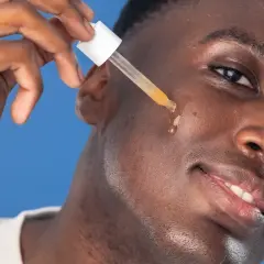 Man applicerar azelaic acid serum med pipett på kinden.