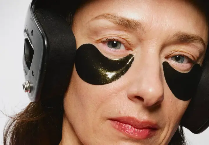 Närbild på en kvinna med mogen hud, bärandes svarta ögonlappar och hörlurar.