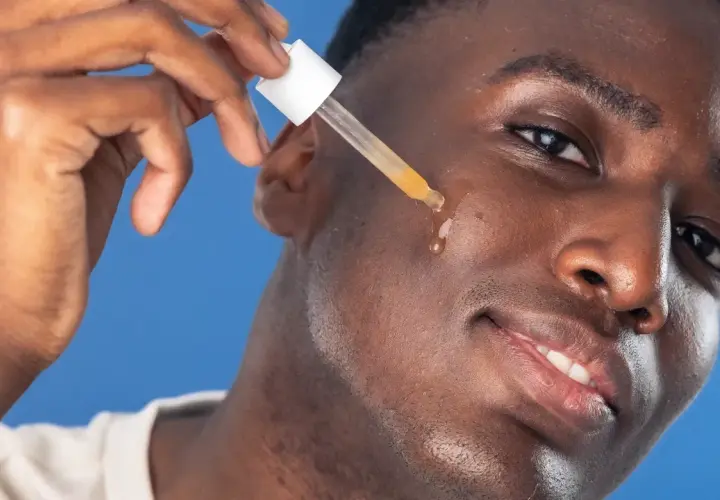 Man applicerar azelaic acid serum med pipett på kinden.