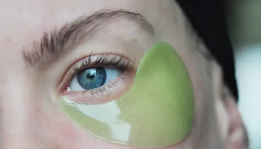 En ljusgrön eye patch sitter perfekt under ögat, följer hudens konturer. Visar hur eye patches ska sitta för maximal effekt.