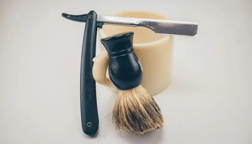 Rakborste, mugg och rakkniv redo för att slipa rakblad för en perfekt rakning.