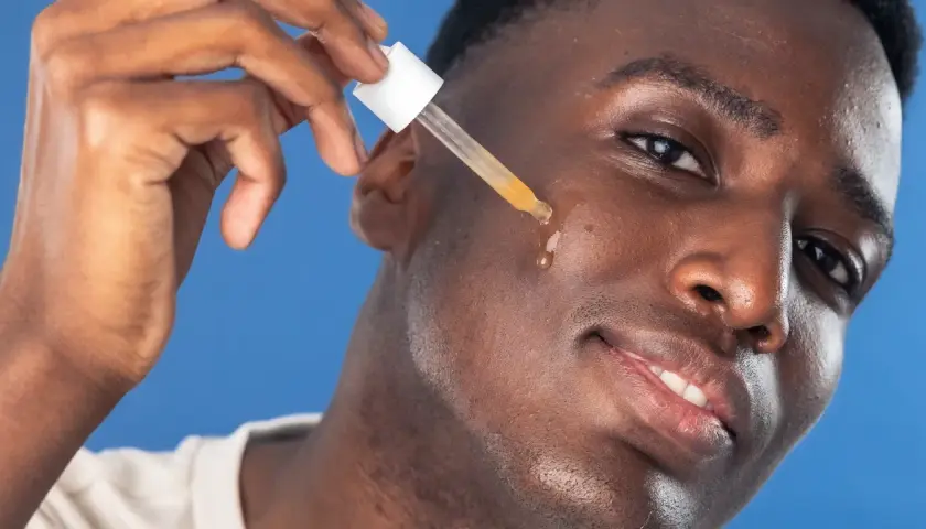 Man applicerar azelaic acid serum med pipett på kinden.