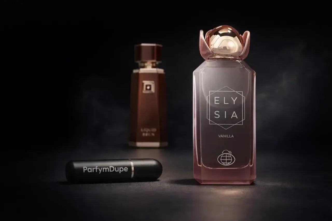 Ett lyxigt parfymval med flaskor i fokus. En rosa flaska med texten "ELY SIA VANILLA" och en mörkbrun flaska i bakgrunden. En liten svart reseflaska med texten "ParfymDupe" ligger framför.
