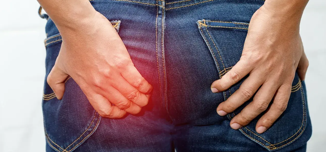 En person i jeans kliar sig i rumpan, med en röd glöd som indikerar obehag.
