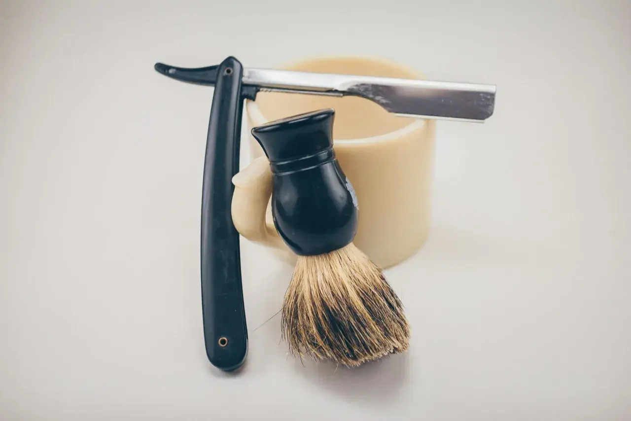 Rakborste, mugg och rakkniv redo för att slipa rakblad för en perfekt rakning.