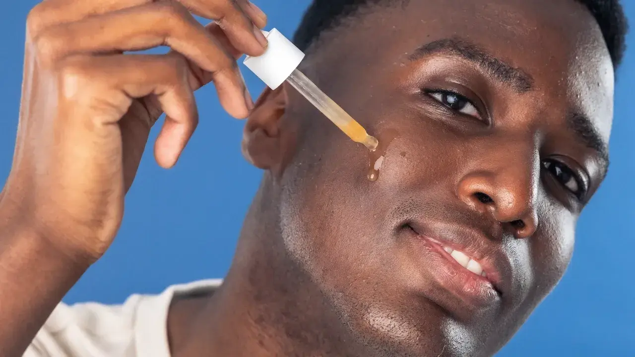 Man applicerar azelaic acid serum med pipett på kinden.