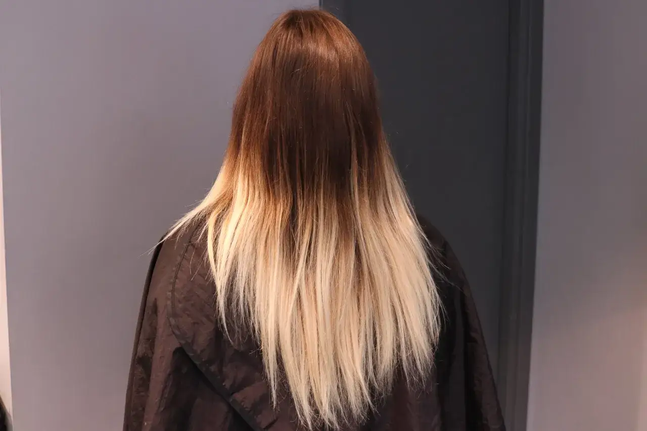 En person med långt hår som går från mörkbrun till ljusblond.