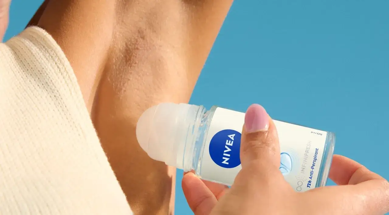 En hand applicerar Nivea InfiniFresh roll-on deodorant under armen för att motverka att man svettas mycket under armarna.