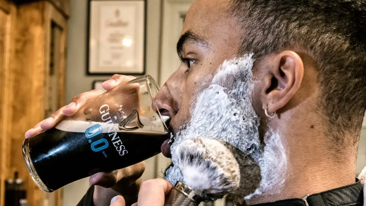 Man med lödder och rakborste dricker Guinness. En perfekt start på en november mustasch.
